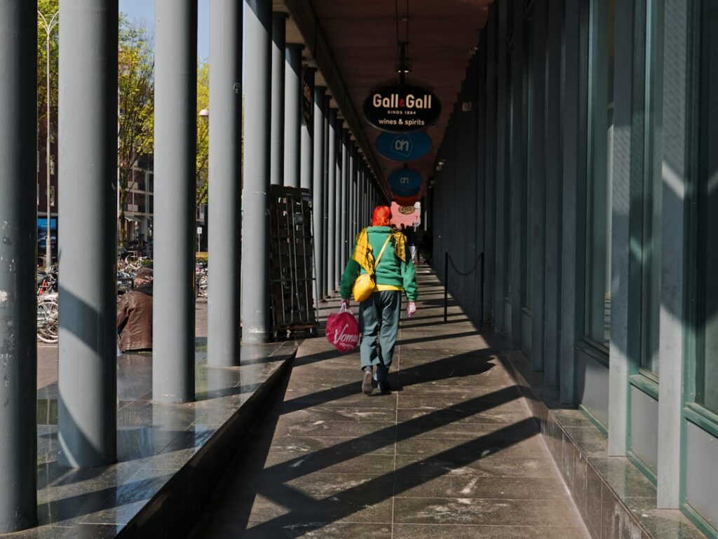 A person walks down a shadowed walkway.