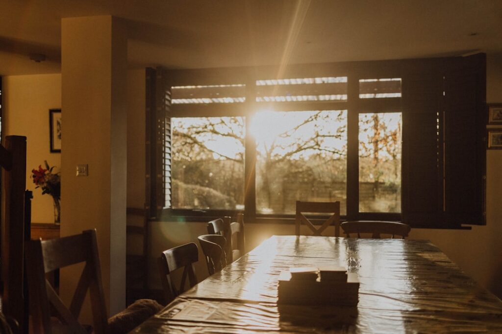 Sunlight streams through a large window onto a dining table.