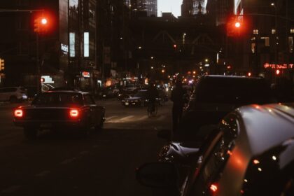 Cars at a city intersection at night with traffic lights.