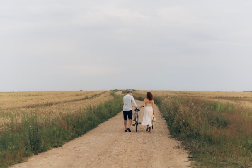 Couple walking with a bicycle on a dirt road
