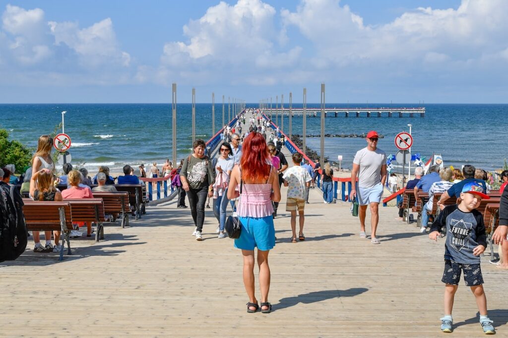 People walking on a pier towards the ocean