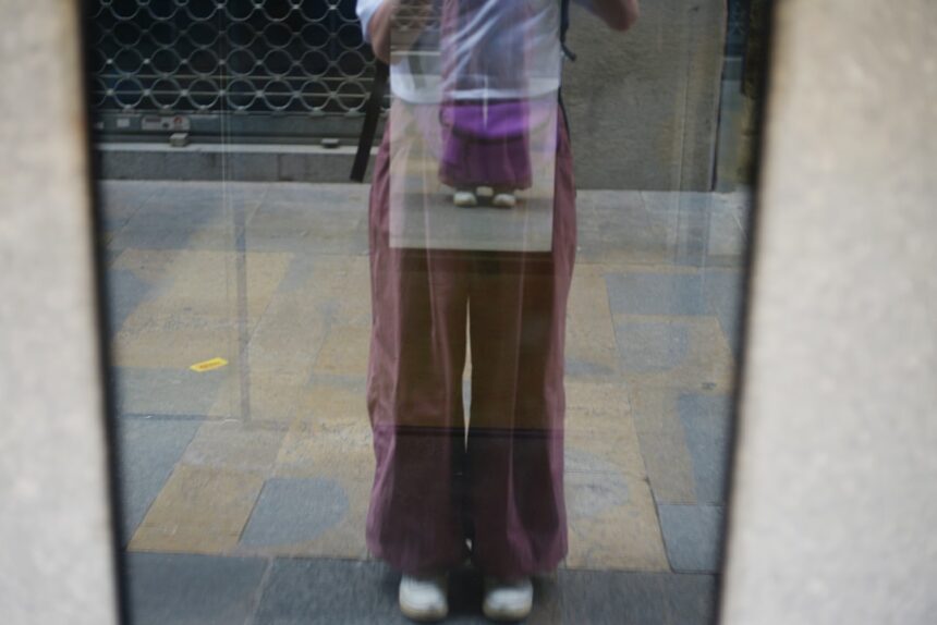 Reflection of a person wearing purple pants in a mirror.