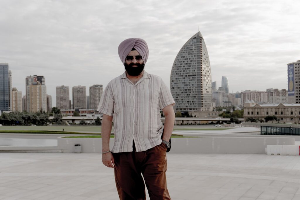 Man in turban standing with city skyline behind him