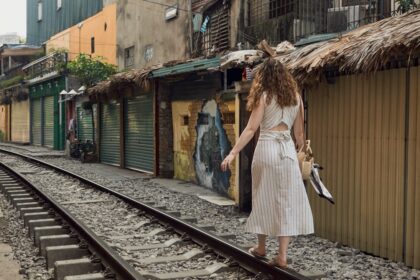 A woman in a white dress walking down a train track