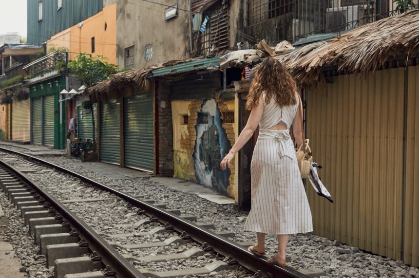 A woman in a white dress walking down a train track
