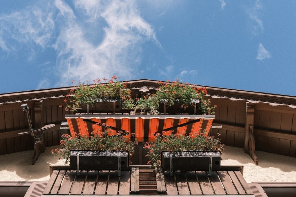 Balcony with flowers and orange awning under blue sky