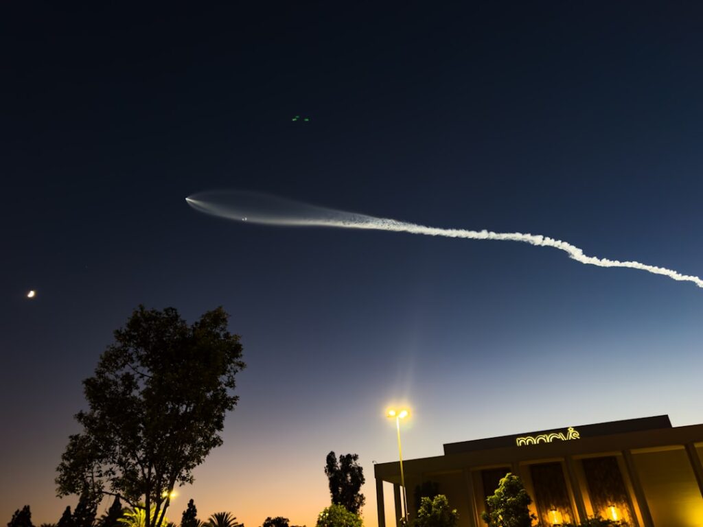 Rocket trail in the night sky above buildings