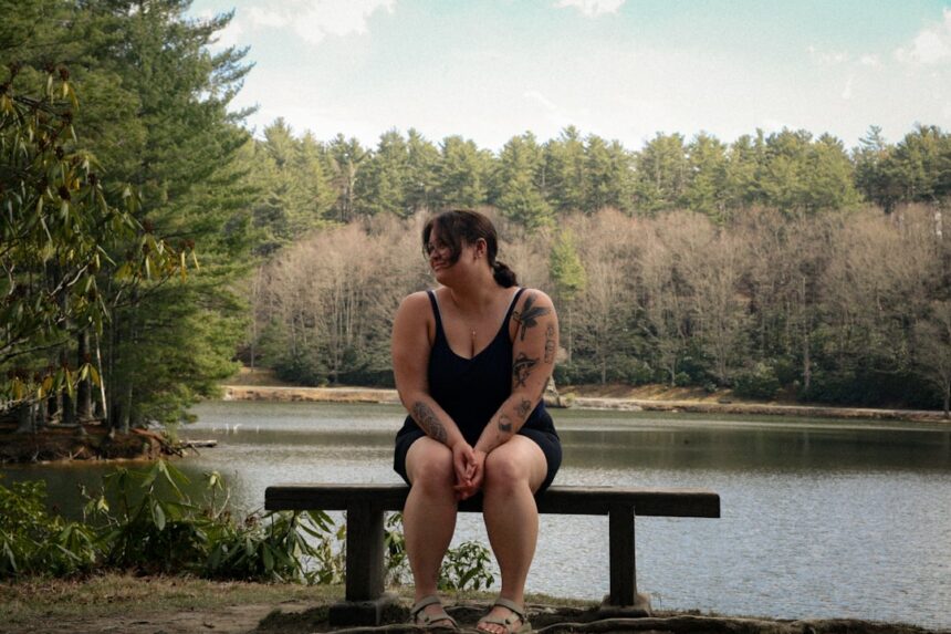 Woman sitting on bench by a lake