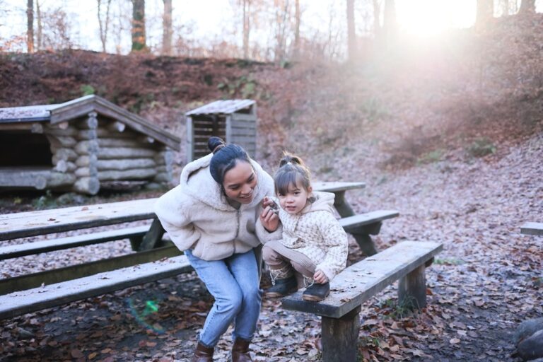 Woman and child sitting on a wooden bench outdoors.