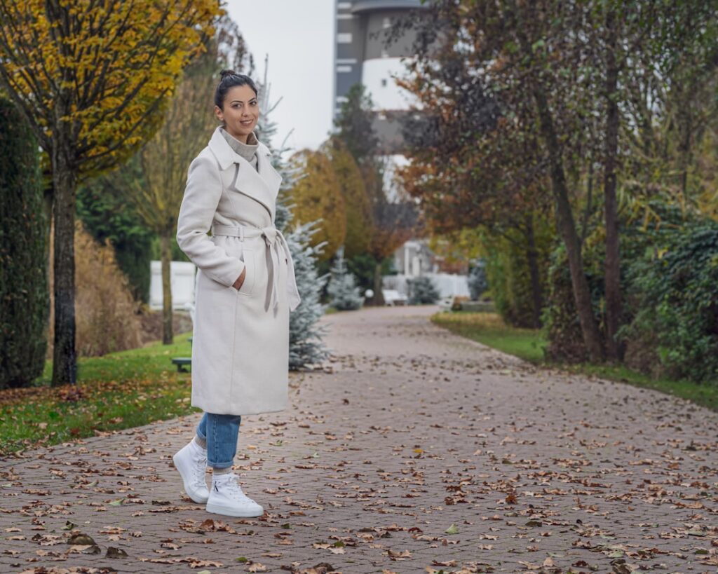 a woman in a trench coat standing on a sidewalk