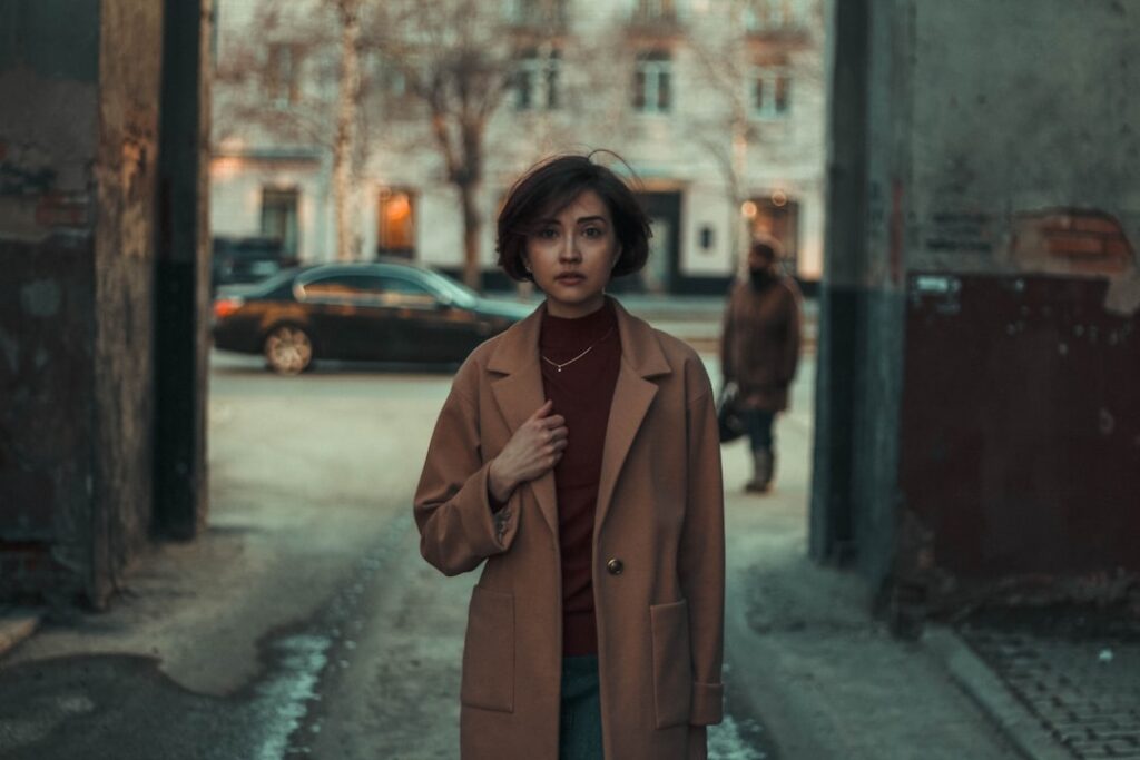 a woman in a brown coat standing on a street