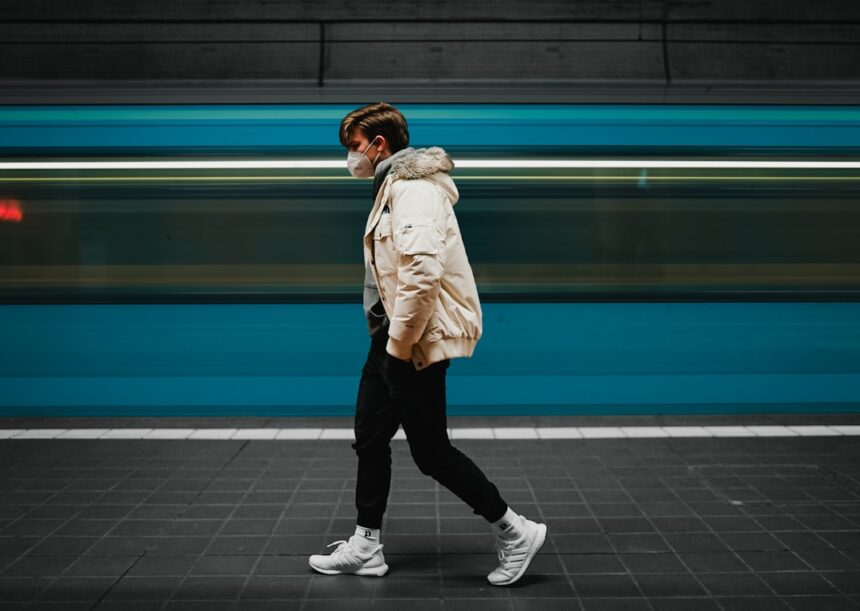 woman in beige coat and black pants standing on gray floor tiles