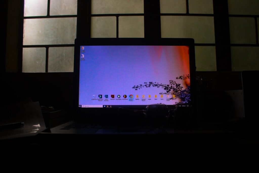 A laptop displaying a colorful desktop in a dark room.