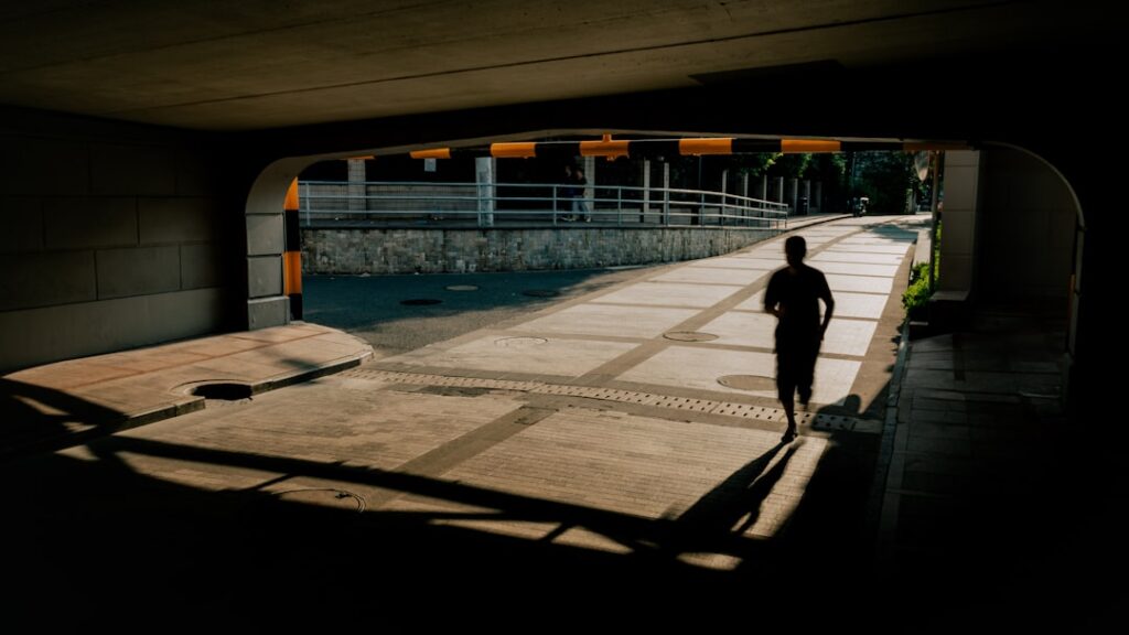 Person running through sunlit underpass path