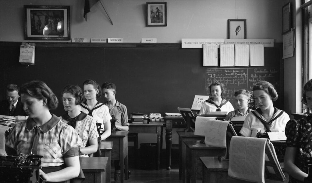 Students in a classroom with typewriters.