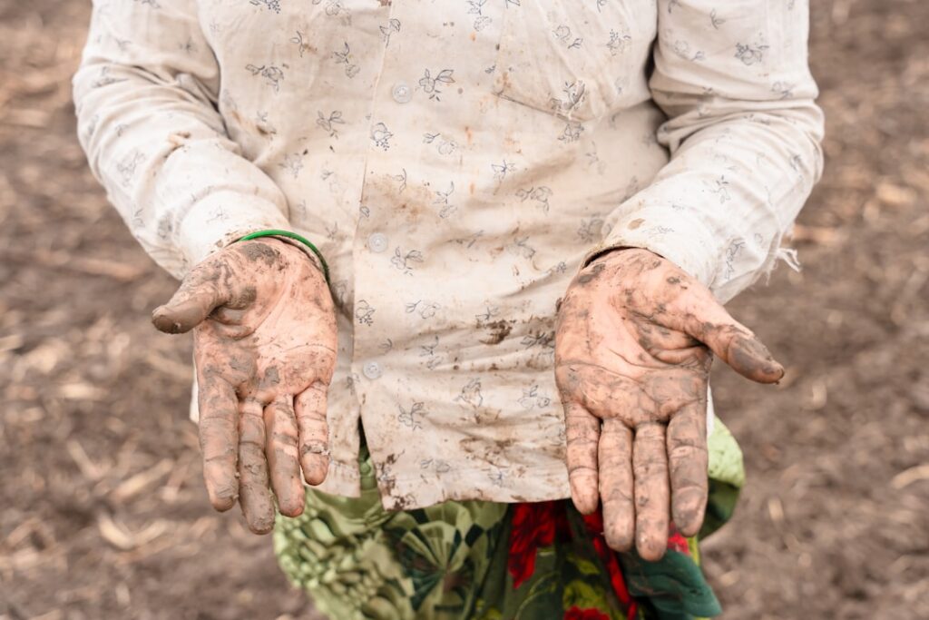 a person with dirty hands standing in a field