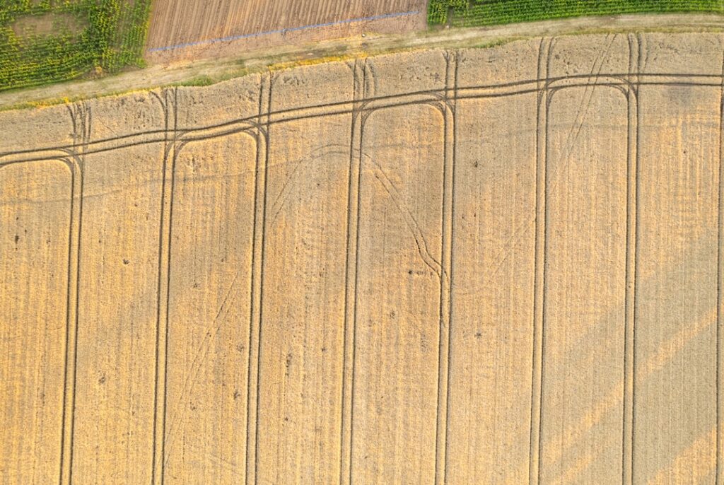An aerial view of a farm field with a fence