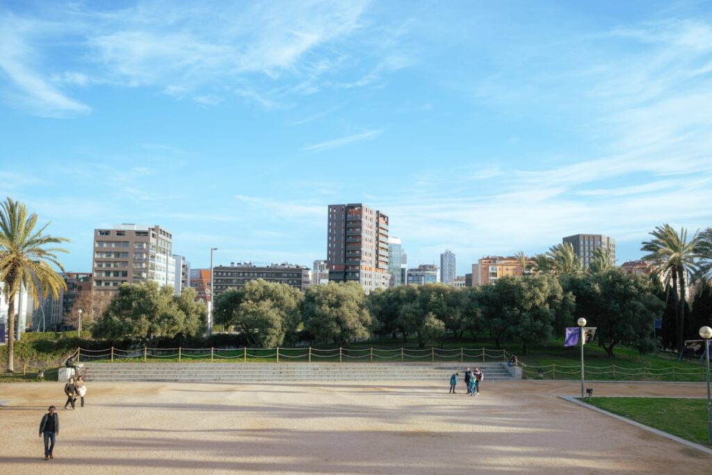 City skyline with buildings, trees, and people walking