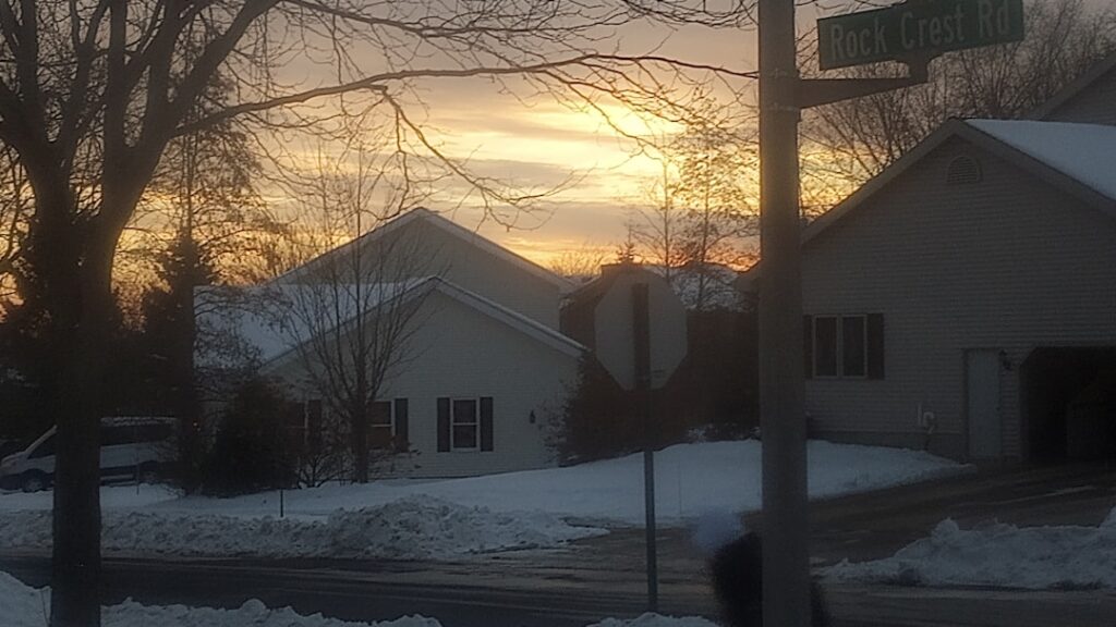 Snowy neighborhood street at sunset