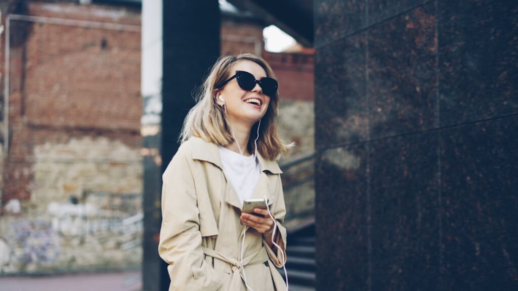 Young woman in sunglasses listening to music outdoors