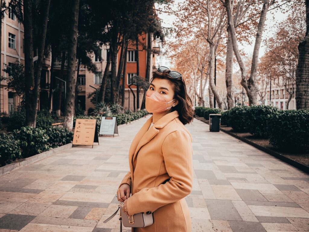 a woman in a tan coat is standing on a sidewalk