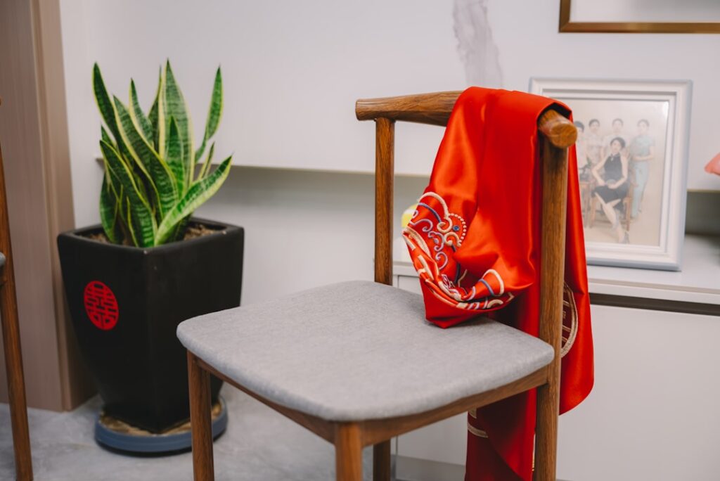 A red garment hangs on a wooden chair.