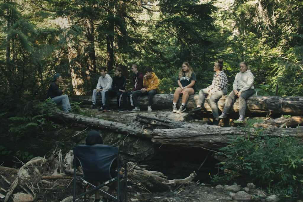 a group of people sitting on a log in the woods