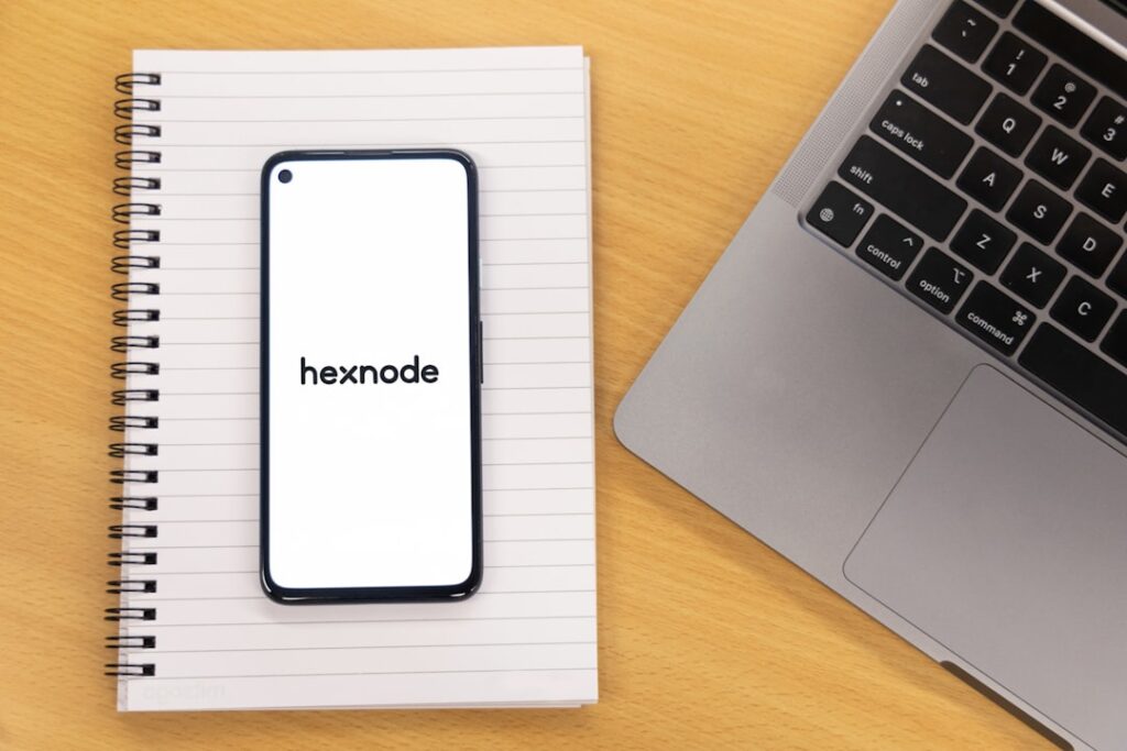 a notebook with the word hexnode written on it next to a laptop