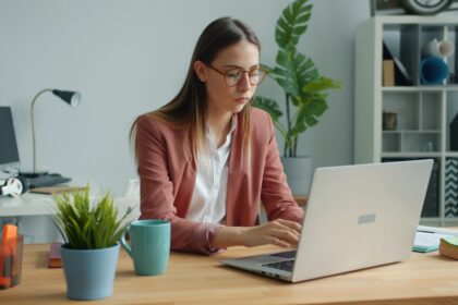 Young woman working on a laptop at a desk.