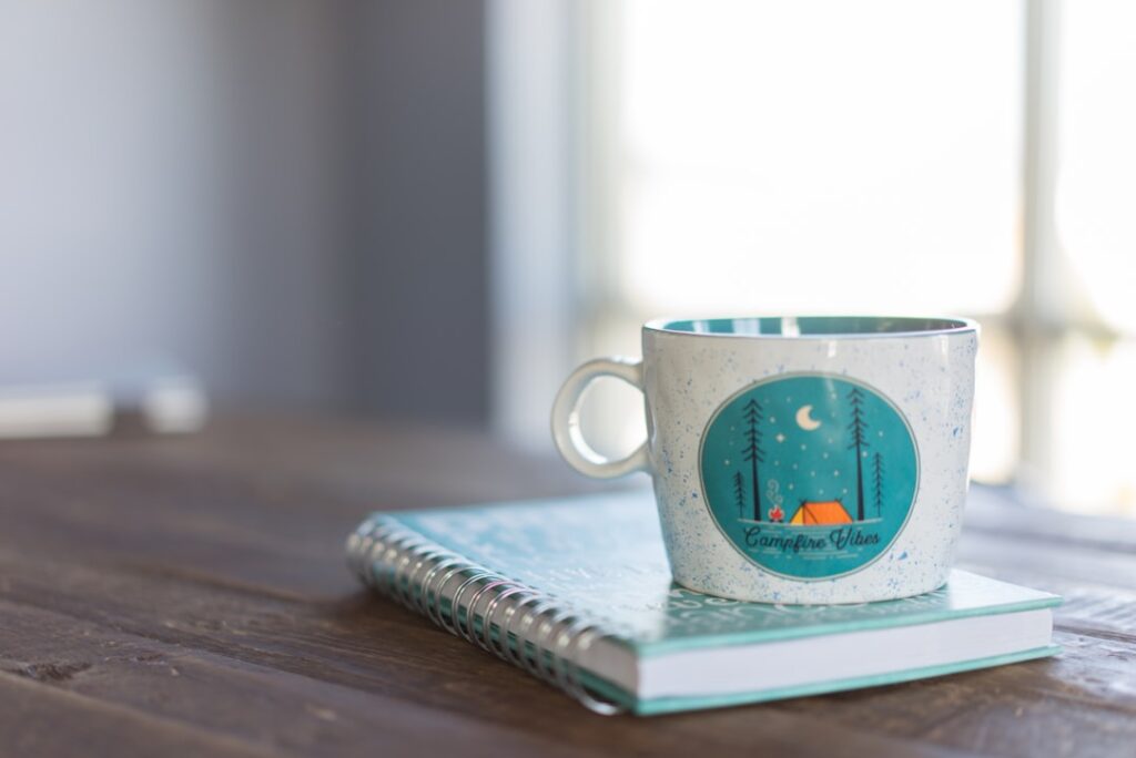 white and blue ceramic mug on notebook