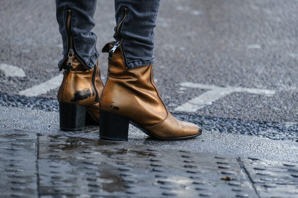 person in brown leather boots standing on gray concrete road during daytime